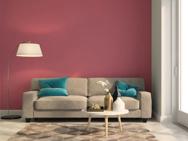 Living room interior design with a red sofa on white coloured wall.